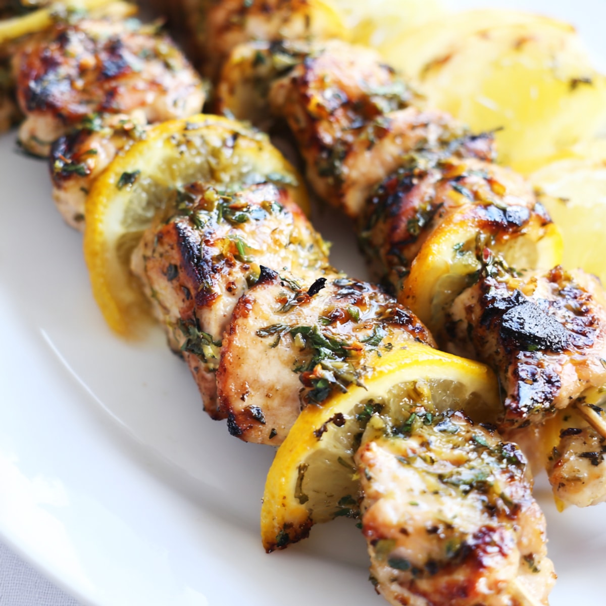 Savory Grilled Lemon Herb Chicken Skewers sizzling on the grill, fragrant with lemon and oregano.
