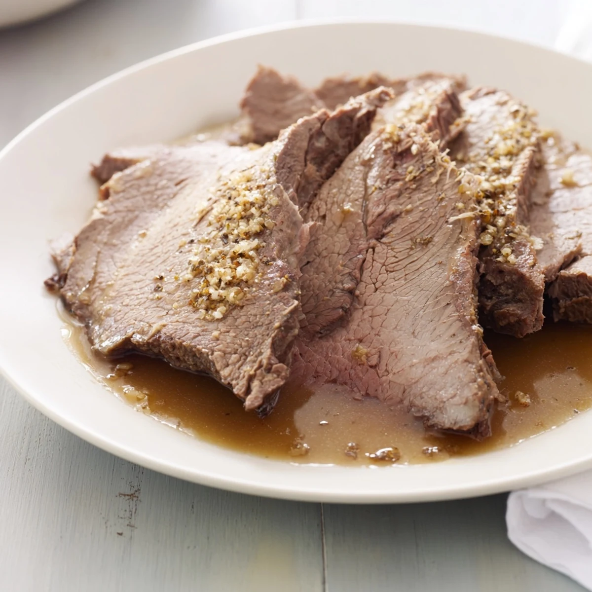 Juicy Budget Holiday Chuck Roast, falling apart tender, simmered in a rich broth with onion flavor.