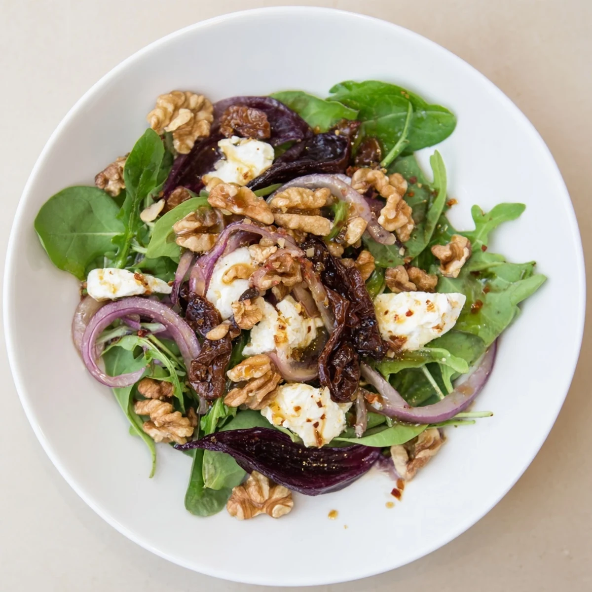 A close-up shot of the Spiced Honey and Date Goat Cheese Salad, drizzled with warm dressing.