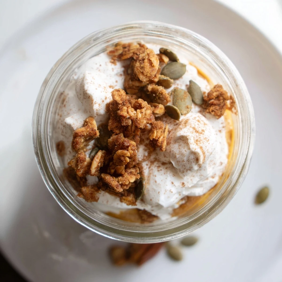   Homemade pumpkin yogurt parfait in a clear glass, ready for a quick and healthy snack or dessert.
