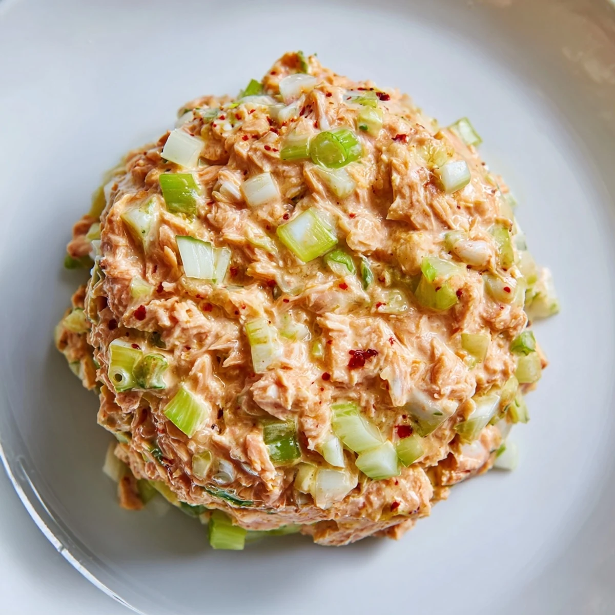 A close-up of Spicy Zesty Tuna Salad showing creamy spicy mayo, diced celery, and a lemon wedge garnish.