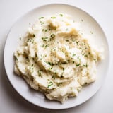 A bowl of fluffy, flavorful cauliflower mash dotted with fresh herbs for a comforting dinner.