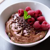 Dark, velvety Avocado Chocolate Mousse presented beautifully with fresh raspberries and shaved chocolate.