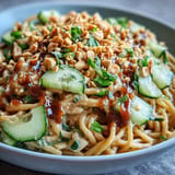 Vibrant Cold Peanut Sesame Noodles topped with crisp cucumber and crunchy peanuts.