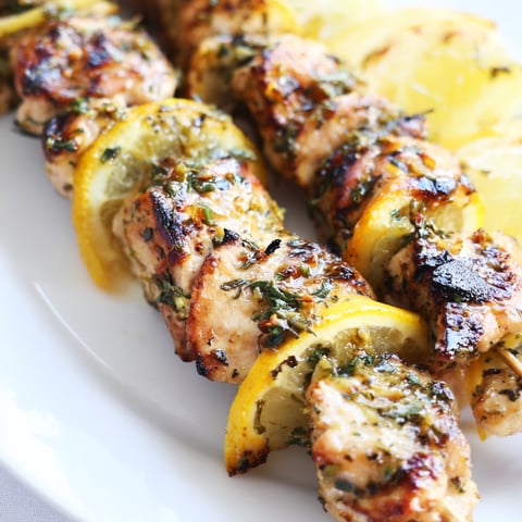 Savory Grilled Lemon Herb Chicken Skewers sizzling on the grill, fragrant with lemon and oregano.