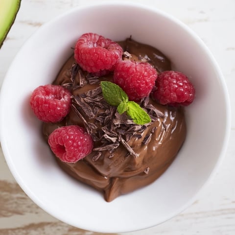 Creamy Avocado Chocolate Mousse: a decadent dessert topped with bright red fresh raspberries.