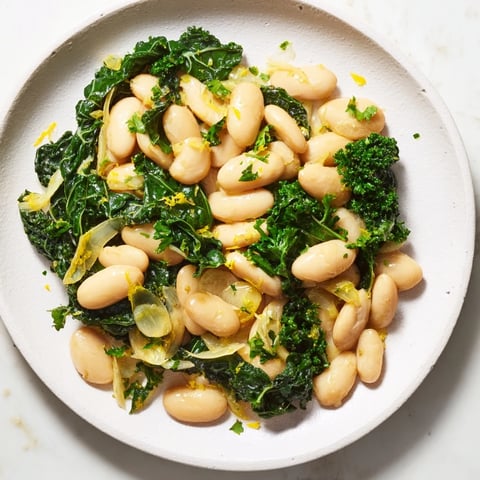 Steaming bowl of Garlicky Beans with Winter Greens, a rustic Mediterranean dish, ready to be enjoyed.
