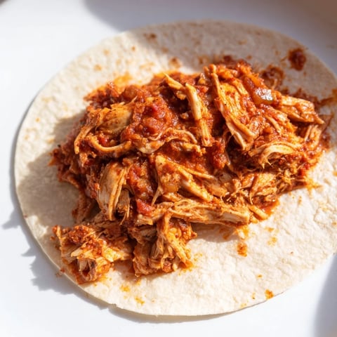 Steaming Crock-Pot Shredded Chicken Tacos piled high with fresh toppings like cilantro and diced tomatoes.