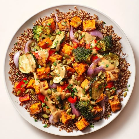 Vibrant quinoa bowl with roasted seasonal veggies, drizzled with creamy lemon-tahini dressing, ready to eat.