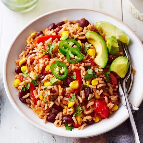 Steaming bowl of One-Pot Mexican Rice & Beans, vibrant and flavorful, garnished with fresh cilantro and lime wedges.