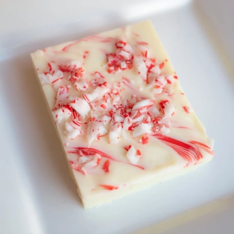 Festive White Chocolate Peppermint Bark Fudge squares, swirled with peppermint, awaiting a sweet bite.
