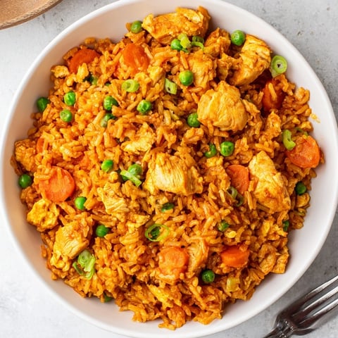 Golden, creamy butter chicken sauce clings to fluffy rice and vibrant peas and carrots in this savory fusion dish.