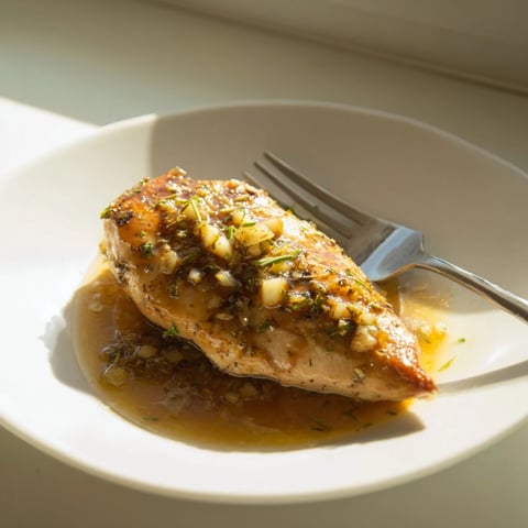 Golden-brown chicken breasts glazed in a shiny honey Dijon sauce, simmering in a skillet with fresh herbs and garlic.