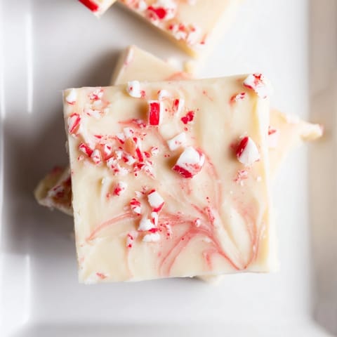 Smooth, creamy White Chocolate Peppermint Bark Fudge topped with vibrant red and white candy cane pieces.