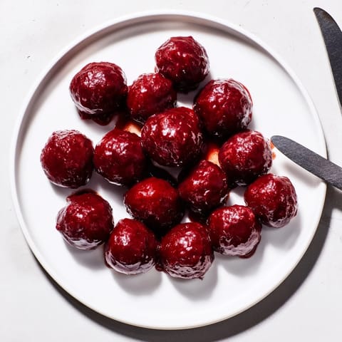 Savory baked cherry-glazed meatballs, coated in a homemade, tangy glaze, perfect for a flavorful snack.