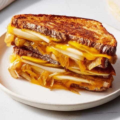 Warm, gooey Caramelized Onion, Apple & Cheddar Grilled Cheese with visible apple slices and cheese pull.