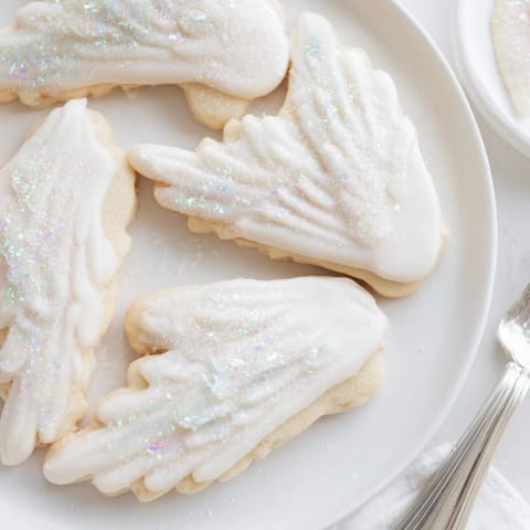 Freshly baked Angel Wings sugar cookies, arranged invitingly on a white plate, ready to enjoy.