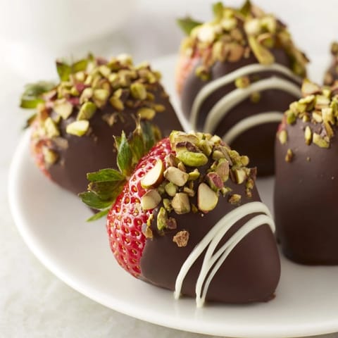 Close up shot of glistening dark chocolate covered strawberry dips, ready for a delicious treat.