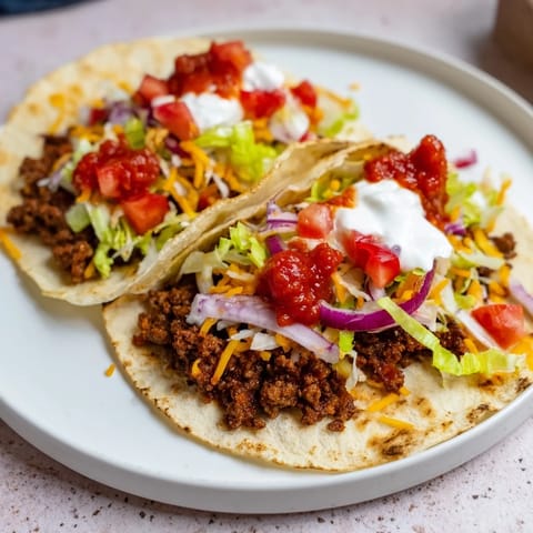 Sizzling close-up of crispy smashed tacos featuring seasoned beef and vibrant garnishes.