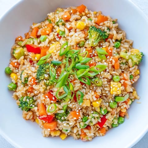 Steaming hot Vegetable Fried Rice in a skillet, featuring crisp broccoli florets and golden grains tossed with ginger and soy sauce.