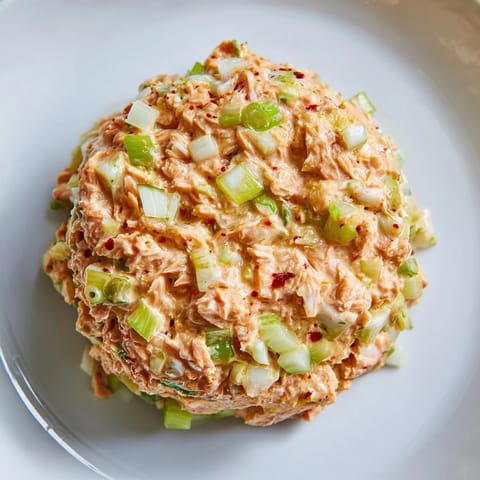 A close-up of Spicy Zesty Tuna Salad showing creamy spicy mayo, diced celery, and a lemon wedge garnish.