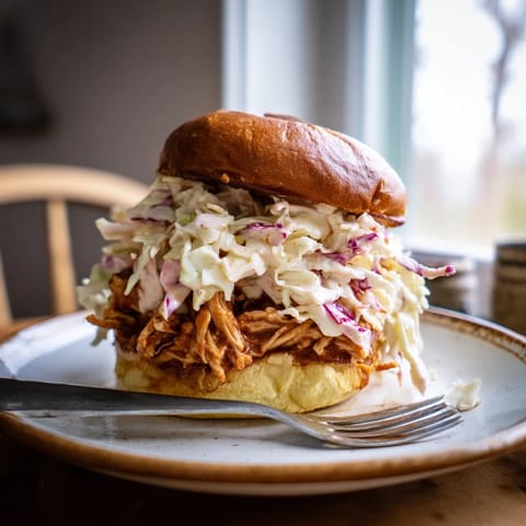 Homemade pulled barbecue chicken sandwich served on a buttery brioche bun with creamy slaw.  