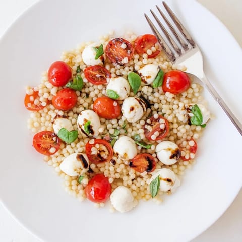 Colorful bowl of Caprese Couscous Salad featuring juicy tomatoes, creamy mozzarella, and fragrant basil, ready for a quick weeknight dinner.