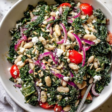 Hearty White Bean and Kale Salad served in a rustic bowl with halved cherry tomatoes and thinly sliced red onion.