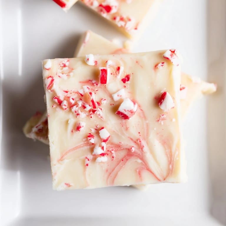 Smooth, creamy White Chocolate Peppermint Bark Fudge topped with vibrant red and white candy cane pieces.