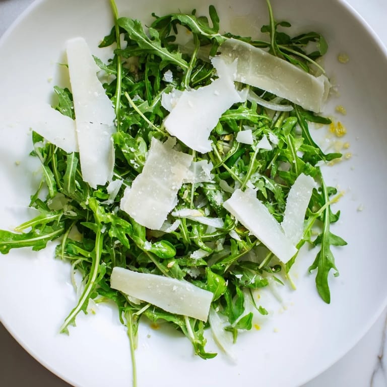 Arugula salad with lemon dressing, perfectly tossed and waiting to be topped with Parmesan.