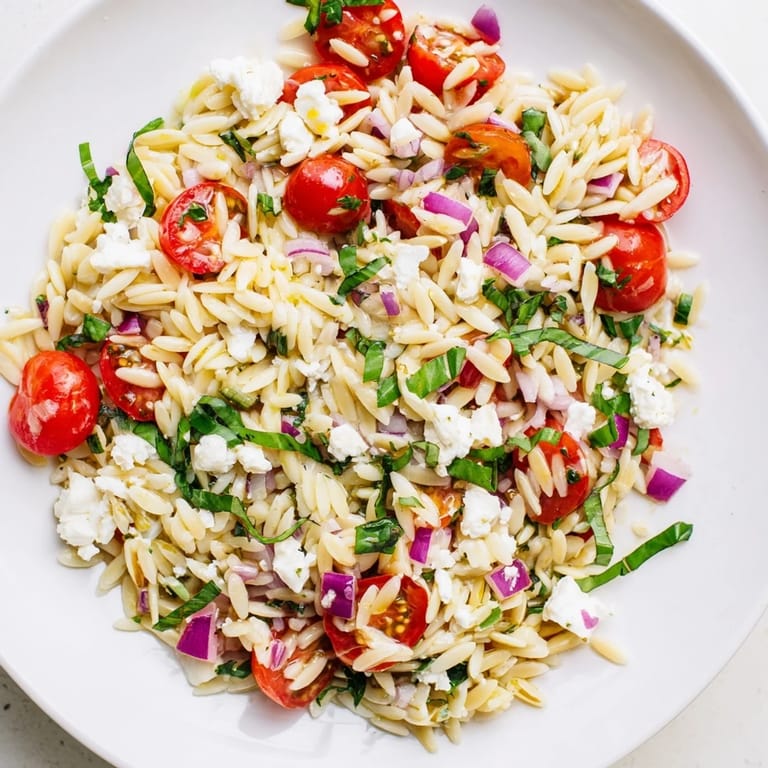 A beautiful bowl of Tomato Feta Orzo showcasing colorful tomatoes, creamy feta, and fresh herbs.
