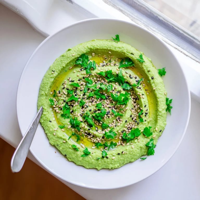 A bright bowl of Edamame Hummus garnished with fresh parsley and sesame seeds, ready for dipping.