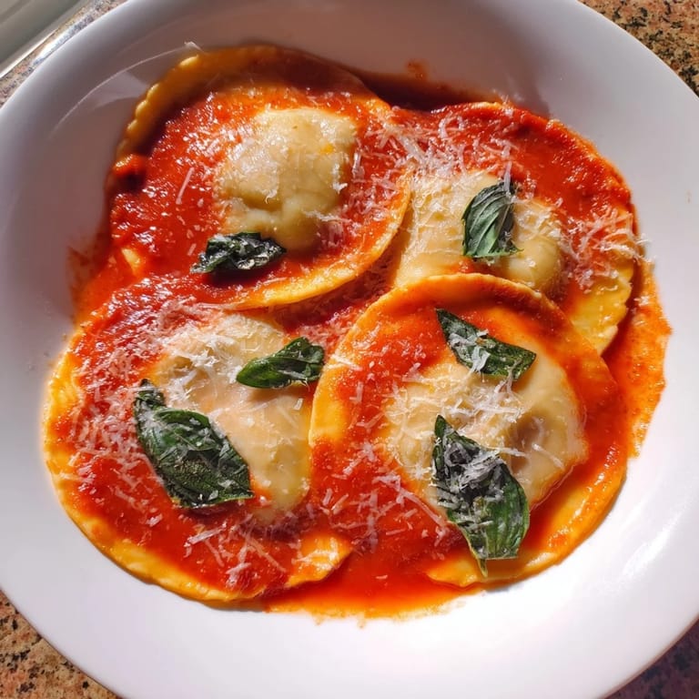 Spinach Ricotta Ravioli topped with marinara and Parmesan, served on a white plate for a cozy Italian dinner.