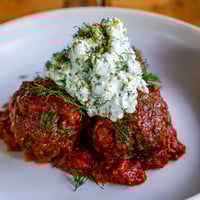 Instant Pot Greek Meatballs, glistening in a vibrant tomato sauce, topped with creamy lemon-feta.