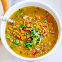 Homemade Indian Mung Bean Soup with fresh cilantro, lemon, and spices in a rustic bowl.