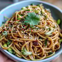 Sesame Ginger Noodle Bowl with crunchy cabbage, vibrant carrots, and a zesty ginger dressing, perfect for a refreshing vegetarian meal.  